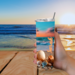 Woman holding seashell tumbler outdoors at table with an ocean view
